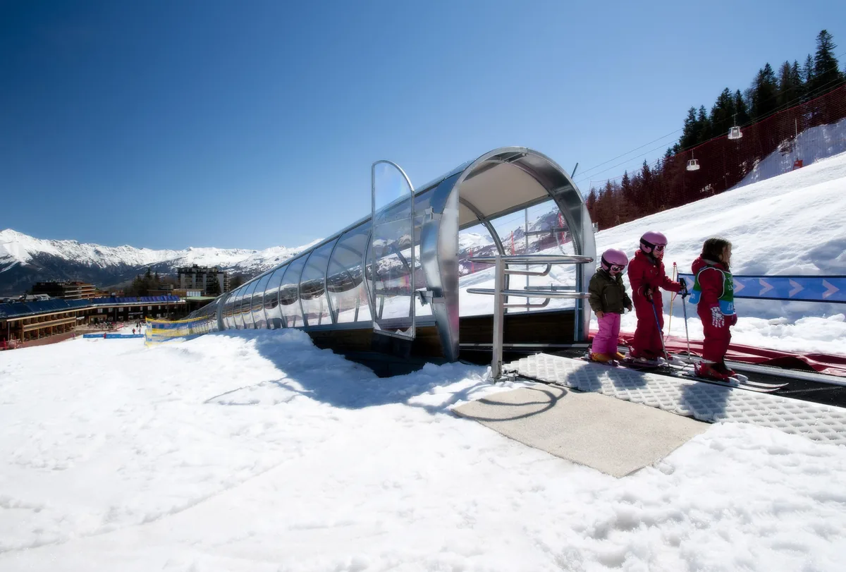 Enfants en cours de ski sur un tapis roulant couvert à Pra Loup